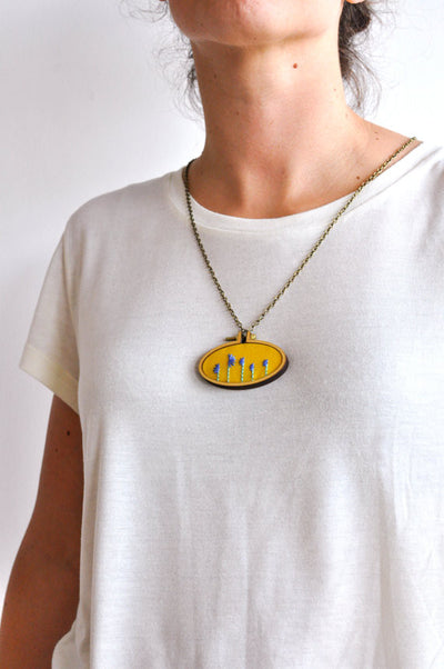 A person wearing the 4cm mini hoop in their palm, showcasing the teeny-tiny scale and smooth wooden finish