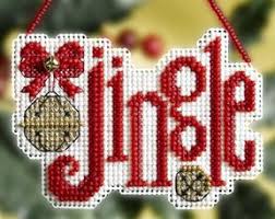 A cross stitch kit depicting the word 'JINGLE' with beads in red, white, and gold colors, completed needlework presented.