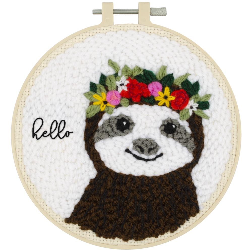 Embroidery hoop kit depicting a sloth with a floral wreath and the text 'Hello' on a white background, framed in a 6-inch plastic hoop.
