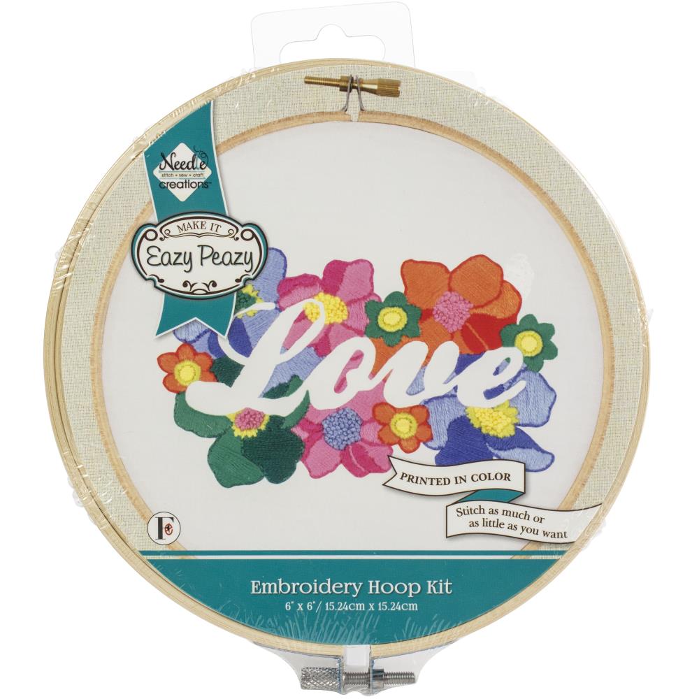 "A complete beginner's embroidery kit from Needle Creations featuring the word 'Love' in an elegant, flowing script. The lettering is surrounded by a charming wreath of simple floral motifs and leaves. The kit includes a pre-stamped canvas panel, a 6-inch embroidery hoop, colorful embroidery thread, a needle, and easy-to-follow instructions. The design is modern, bright, and perfect for home decor