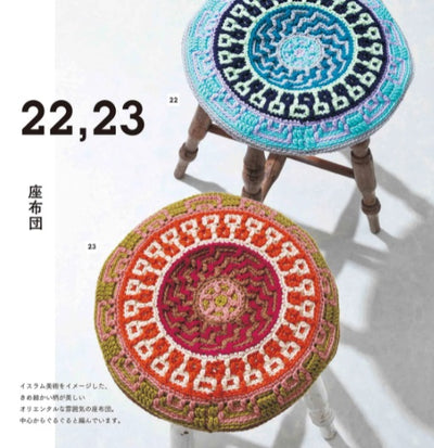 A lifestyle photo of a modern, mosaic-stitched cushion placed on wooden stools.
