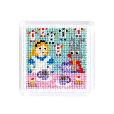 A cross stitch magnet featuring fairy tale characters Alice and the rabbit with decks of cards enjoying an afternoon tea