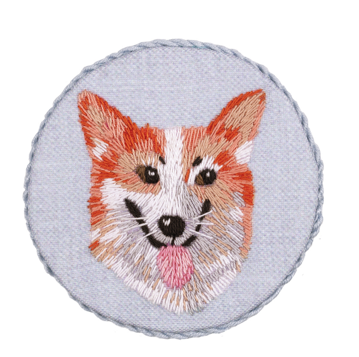 Embroidery brooch of a Welsh Corgi dog with a blue background, stitched in various colors representing the dog's fur and features.