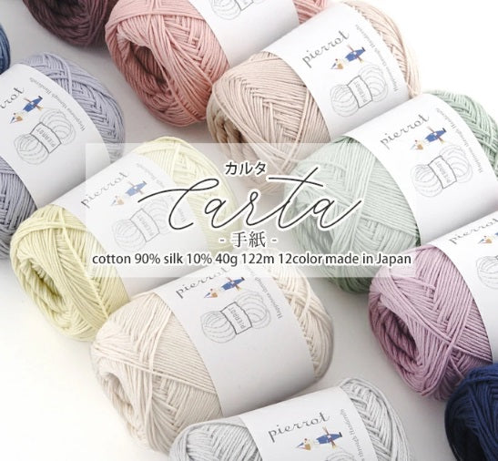 Multiple skeins of Pierrot Carta yarn in various colors arranged neatly. The yarn is made of cotton and silk, and the packaging indicates it is made in Japan.