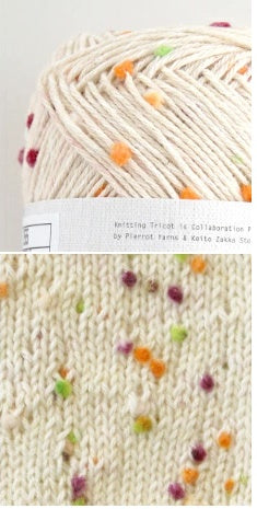 Pierrot Framboise yarn with purple, green and orange tiny pom pom multicolored speckles, arranged on a surface with labels indicating the brand and type.