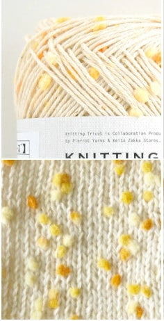 Pierrot Framboise yarn with  yellow and orange tiny pompom multicolored speckles, arranged on a surface with labels indicating the brand and type.