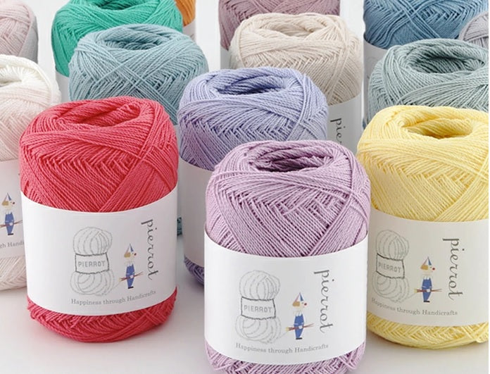 Multiple skeins of Pierrot New Shine Cotton yarn in various pastel colors, displayed neatly with labels in front.