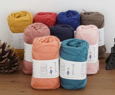 Multiple balls of Pierrot Pure Wool in various colors, showcasing the rich pigment and premium matte finish of this Japanese-made wool