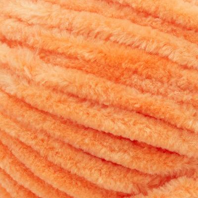 Close-up of Premier Parfait Chunky polyester yarn, highlighting the dense, plush pile and vibrant color in tangerine