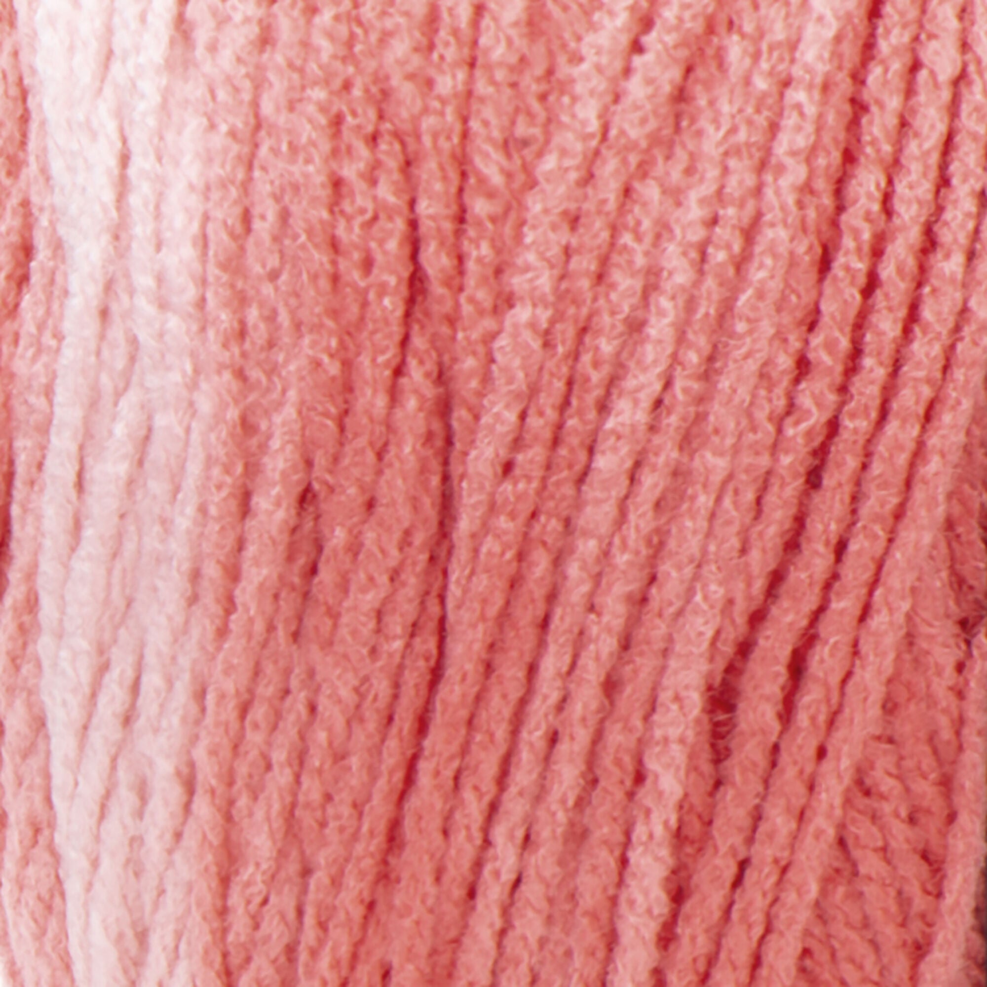 A large 283-gram skein of Red Heart Super Saver Ombre yarn, showing a beautiful gradient transition from a light tint to a deep, saturated shade of coral color. The yarn has a classic 4-ply twist and a soft matte finish, perfect for creating shawls, blankets, and garments with a natural ombré effect