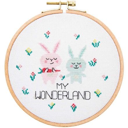Cross stitch kit depicting two cartoon bunny characters with the text 'MY WONDERLAND' around them, on a white background with colorful flowers.