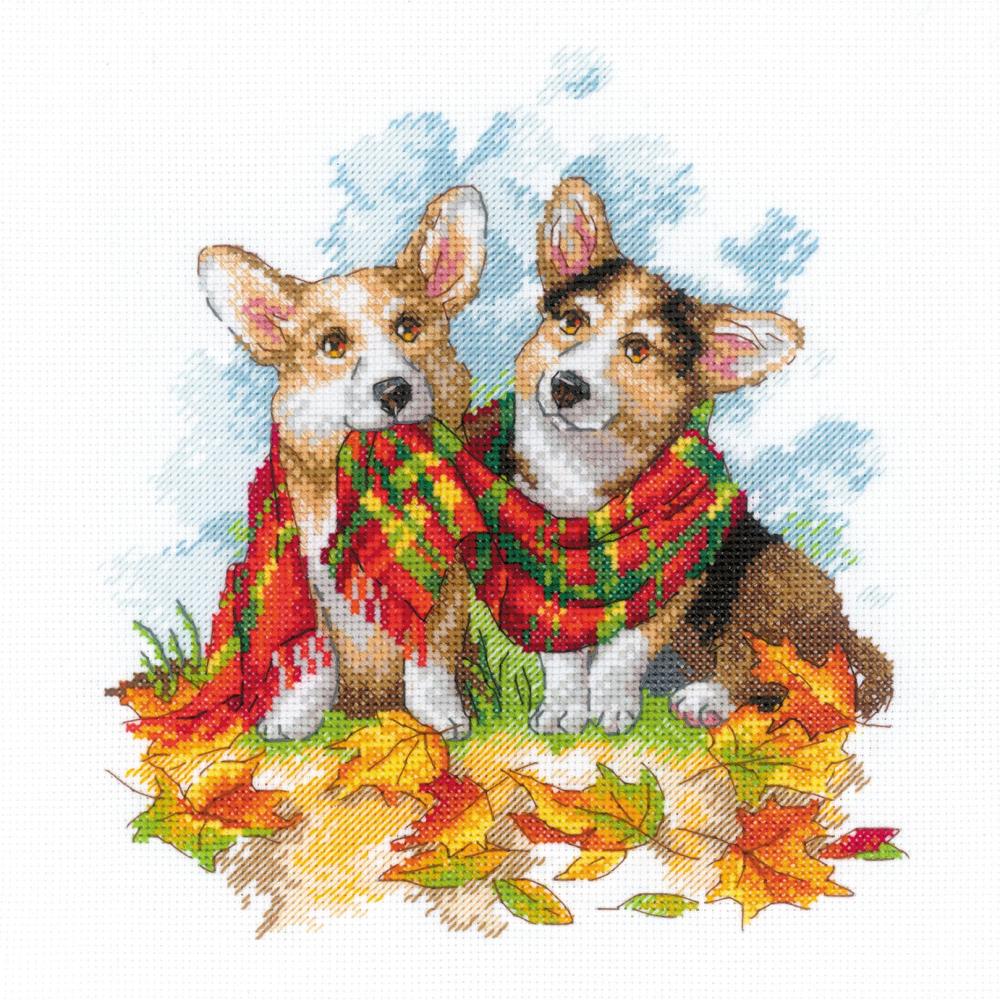 Cross stitch kit image featuring two Corgi dogs wrapped in a blanket with a fall leaves background.