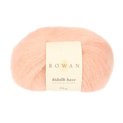 A skein of Rowan Kidsilk Haze yarn in a light pink color with a label wrapped around it.
