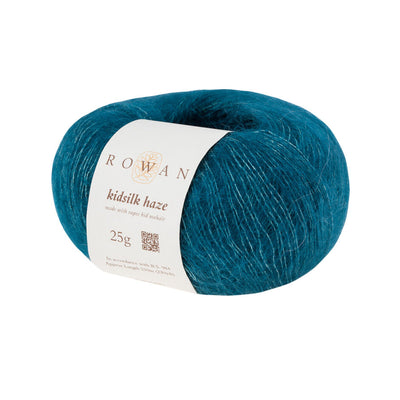 A skein of Rowan Kidsilk Haze yarn in teal blue color with a label wrapped around it.