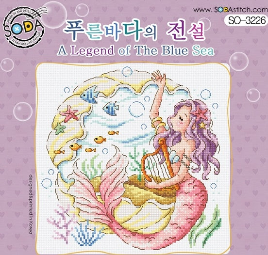 Cross stitch kit image featuring a colorful design with a mermaid sitting on a shell, surrounded by fish and coral, on a pink background with a 'SODA' branding logo at the top.