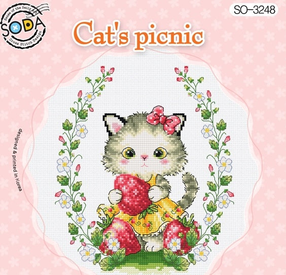 Cross stitch kit image featuring a cartoon cat with a strawberry, flowers, and the text 'Cat's Picnic'.