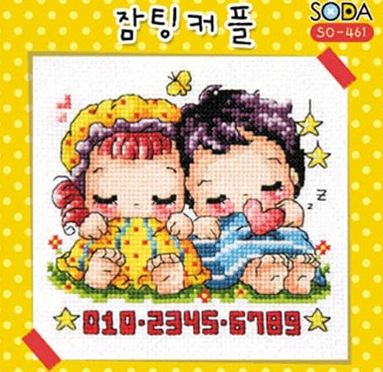 A cross stitch kit image depicting a sleeping couple, with colorful background and various stitched patterns on the fabric.