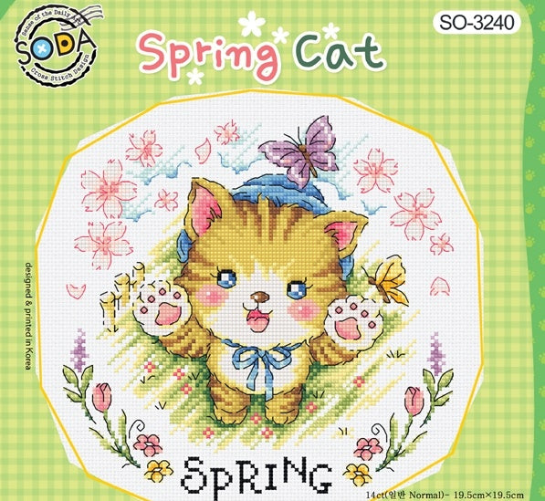 A square-format seasonal cross-stitch kit from SODA (Korea) titled 'Spring Cat.' The design features several whimsical, illustrative cats in a garden setting, surrounded by spring flowers, butterflies, and bright seasonal motifs. The kit includes 14-count white Aida cloth, full skeins of DMC embroidery threads, and a needle. The finished design measures 19.5 cm by 19.5 cm