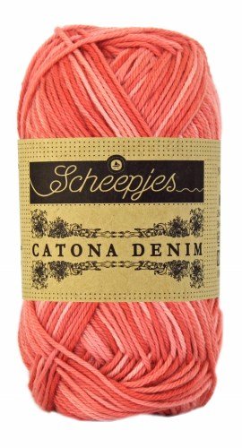 A skein of Catona Denim by Scheepjes, demonstrating the contrast between the white cotton core and the dyed fibers that create an authentic denim texture in coral orange