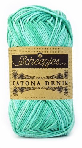 A 50g ball of Scheepjes Catona Denim yarn, showing the 100% natural cotton fibers with a subtle, variegated denim-effect colorway in mint-Jade green