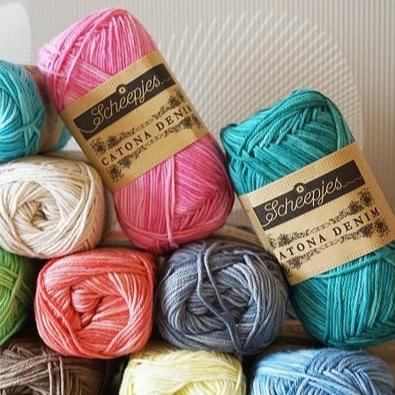 A collection of Scheepjes Catona Denim yarn skeins in various colors.