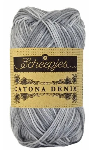 A 50g ball of Scheepjes Catona Denim yarn, showing the 100% natural cotton fibers with a subtle, variegated denim-effect silver/grey colorway