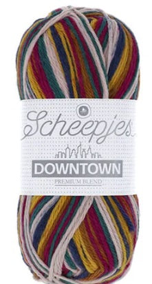 A skein of Scheepjes Downtown self-striping yarn in multicolor, predominantly in shades of red, silver, yellow and navy blue