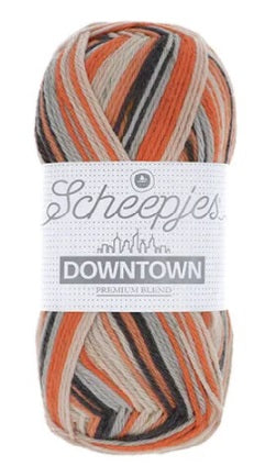 A skein of Scheepjes Downtown self-striping yarn in multicolor, predominantly in shades in orange, dark navy and cream
