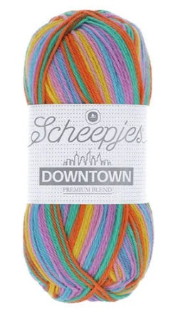 A skein of Scheepjes Downtown self-striping yarn in multicolor, predominantly in shades of Orange Lilac, yellow and green.