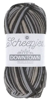 A skein of Scheepjes Downtown self-striping yarn in multicolor, predominantly in shades of grey and black