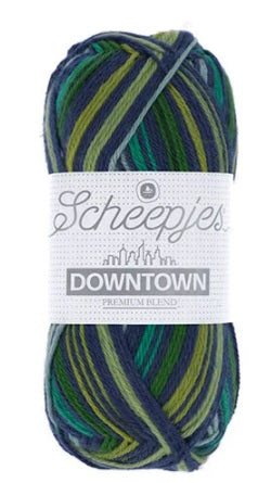 A skein of Scheepjes Downtown self-striping yarn in multicolor, predominantly in shades of blue, and green.