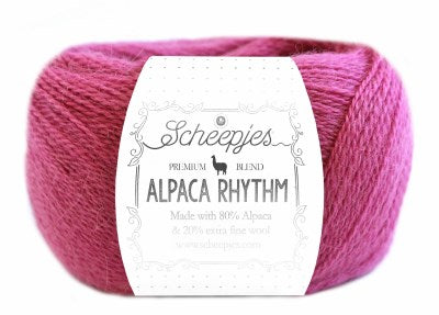 A skein of Scheepjes Alpaca Rhythm yarn in a multicolor pattern, with the brand and product name displayed on the label in dark purple colour.