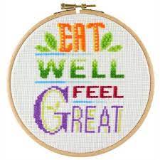 Cross stitch kit depicting the phrase 'EAT WELL FEEL GREAT' with each letter framed in a colorful border, completed and presented on a 6-inch embroidery hoop.