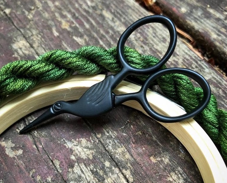 A pair of miniature 'Storklette' embroidery scissors, featuring the classic bird-shaped design in a compact 40x70mm size. Shown in various vibrant and metallic finishes, these stainless steel scissors highlight their sharp precision tips and portable scale, perfect for travel sewing kits.