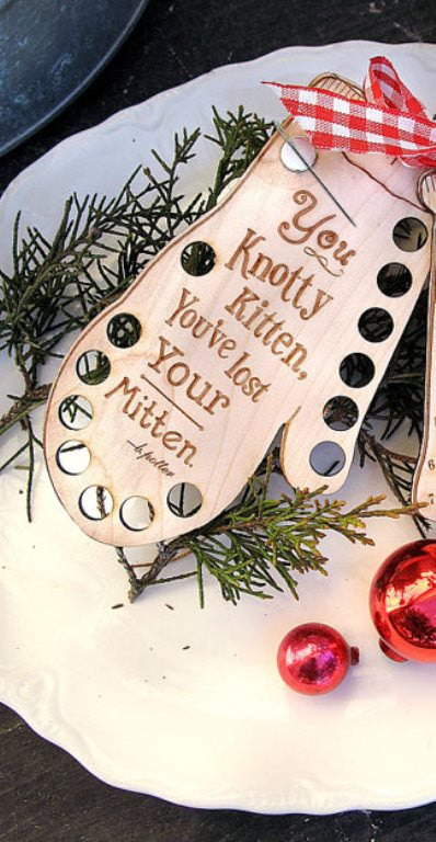 A wooden Christmas-themed floss organizer with a mitten design and text 'You knotty kittens, you lose your mittens'.