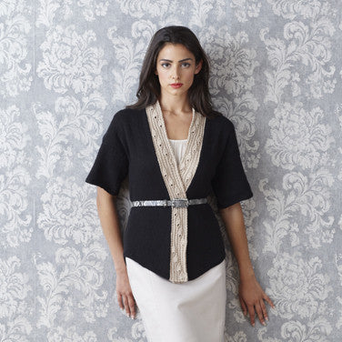 A woman wearing a sophisticated knitted sweater in black and beige neck lace edging from the collection, styled for an elegant evening look