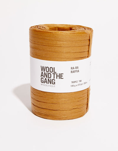 A roll of light brown tropez tan Wool And The Gang Ra-Ra Raffia yarn with a label in the center.