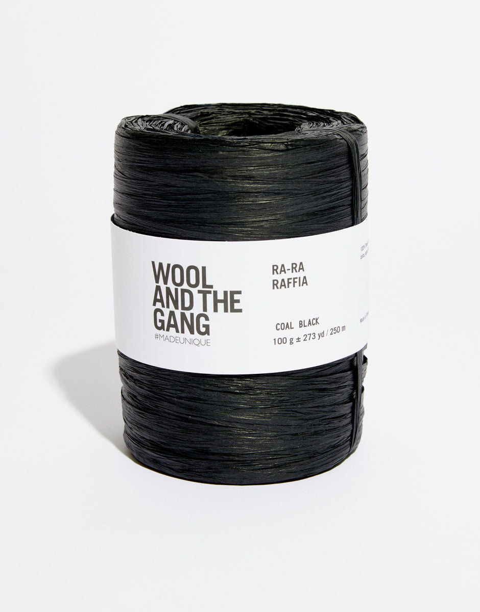 A roll of Black Wool And The Gang Ra-Ra Raffia yarn with a label in the center.