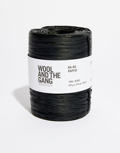 A roll of Black Wool And The Gang Ra-Ra Raffia yarn with a label in the center.