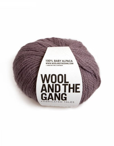 A blue skein of WOOL AND THE GANG Sugar Baby Alpaca yarn with a label in the center in purplish-grey colour