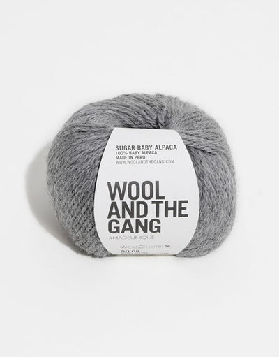 A blue skein of WOOL AND THE GANG Sugar Baby Alpaca yarn with a label in the center in tweed grey colour