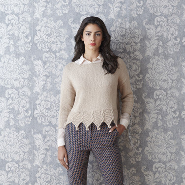 A selection of 12 designs from the Sublime collection, featuring delicate lace cover-ups and striking, elegant sweaters for women. Woman wearing a beige knitted sweater with cable edging at the bottom