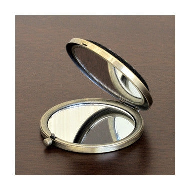 Close-up of the open dual-sided compact mirror, showing the standard and magnifying glass interior and the high-quality hinge construction